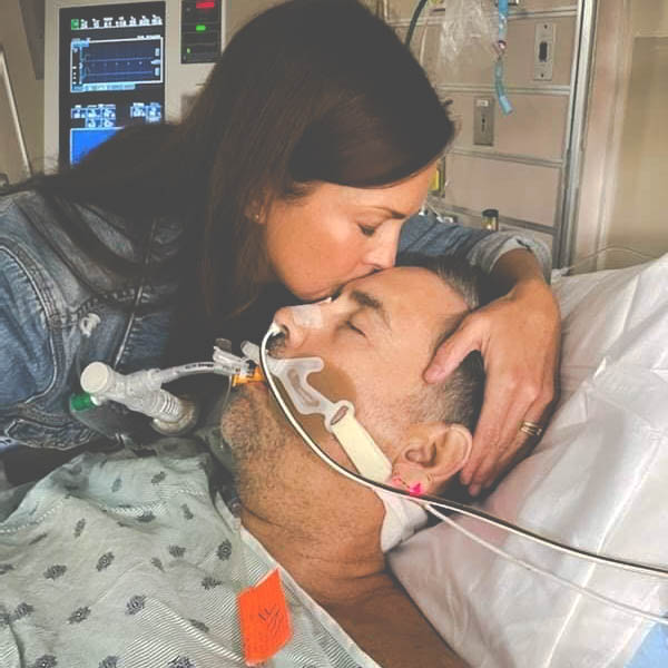 Image: Kristen Walters kisses her husband, Doug's, forehead as he lies in a hospital bed.